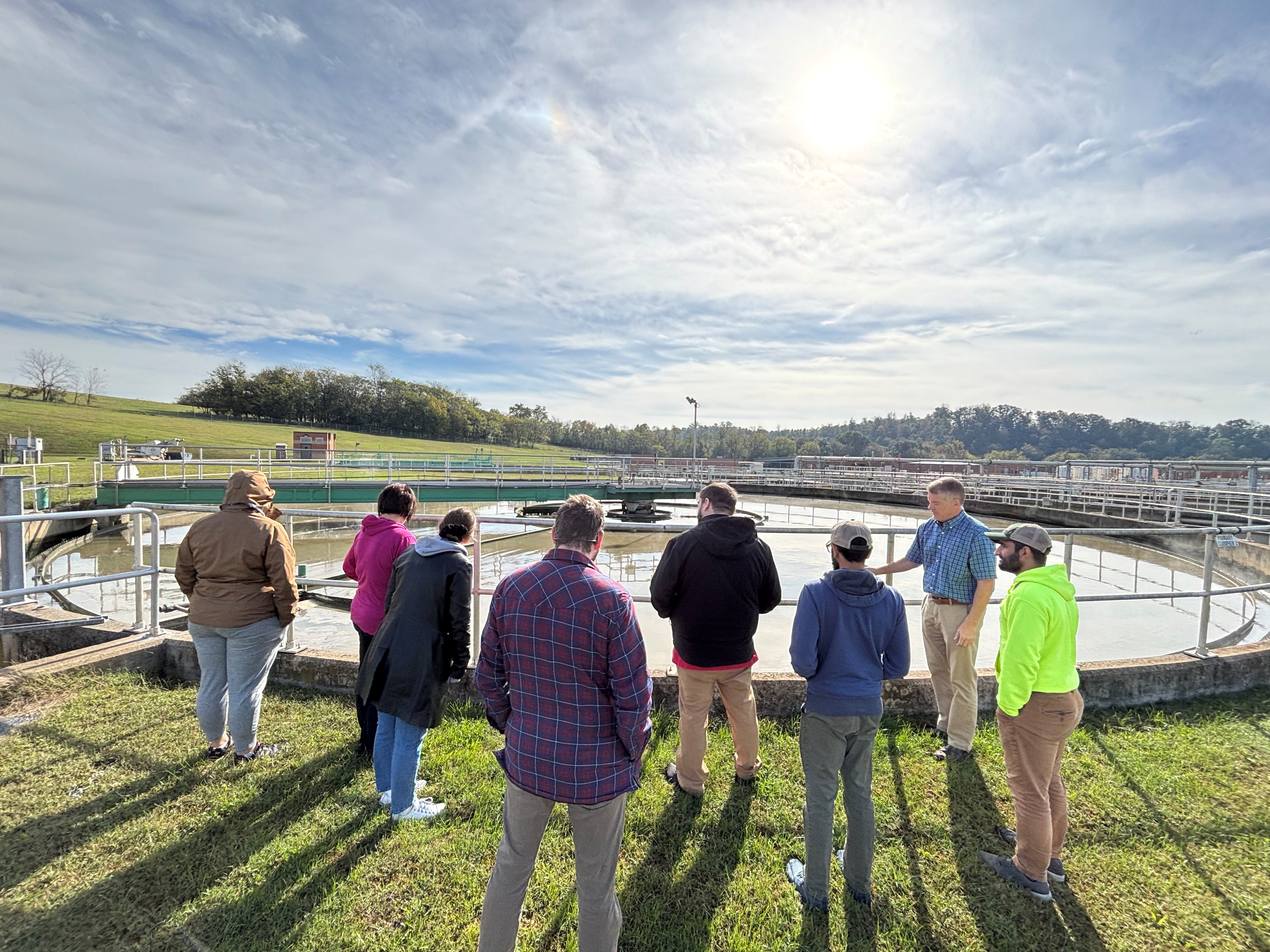 Citizen Academy participants stand outside around an underground water clarification tank at the Harrisonburg-Rockingham Regional Sewer Authority while a staff member teaches about the infrastructure.