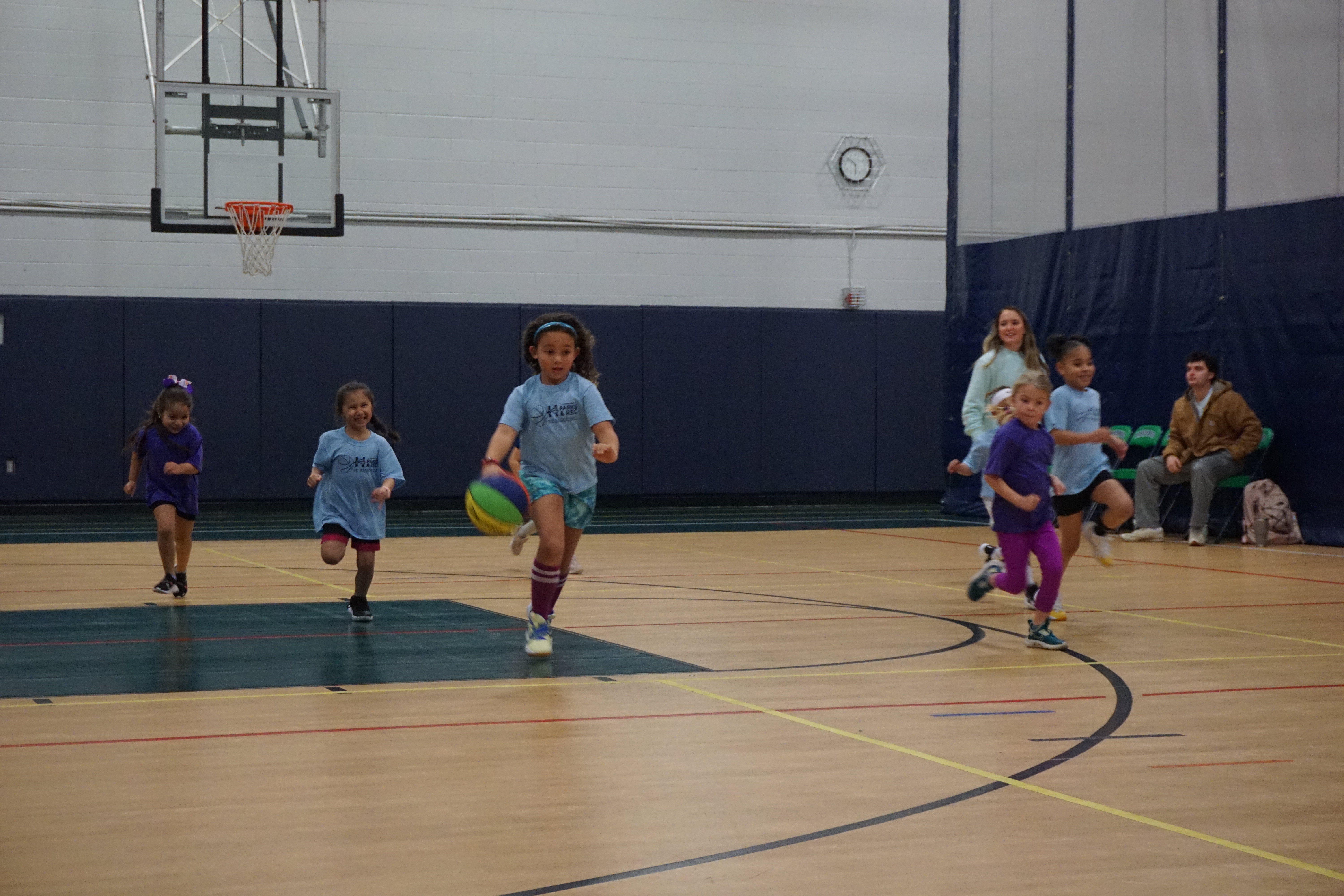 Girls running after a basketball on a court