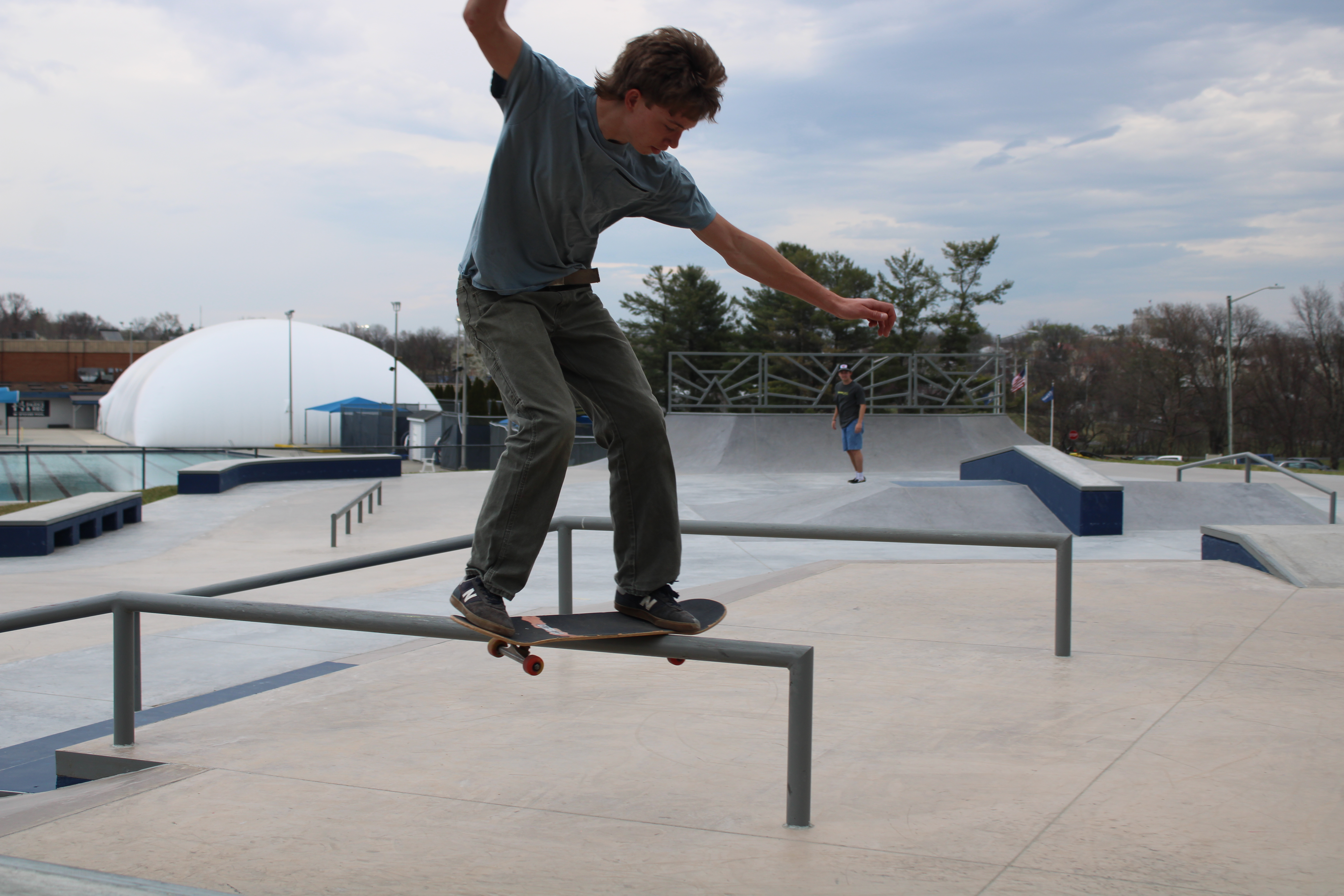 Man riding a skateboard on a rail at the skate park.